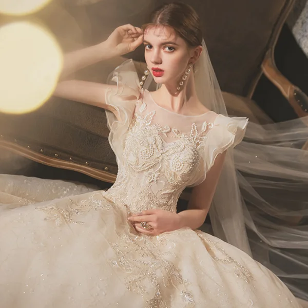 Chic / Belle Champagne La Mariée Robe De Mariée 2020 Robe Boule Transparentes Encolure Dégagée Sans Manches Dos Nu Appliques En Dentelle Perlage Glitter Tulle Chapel Train Volants