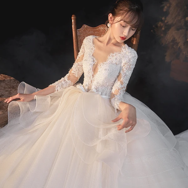 Illusion Champagne La Mariée Robe De Mariée 2020 Robe Boule Transparentes Col v profond Manches Longues Dos Nu Appliques En Dentelle Perlage Noeud Ceinture Glitter Tulle Cathedral Train Volants