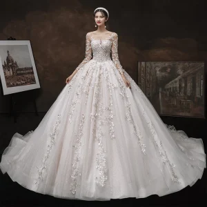 Charmant Champagne Fait Main La Mariée Robe De Mariée 2021 Robe Boule Transparentes Encolure Dégagée Manches Longues Dos Nu Appliques En Dentelle Perlage Glitter Tulle Cathedral Train Volants