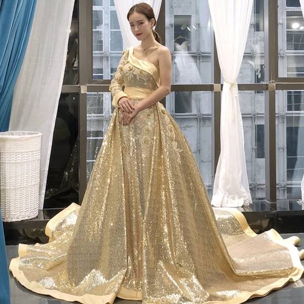 Glitzernden Gold Pailletten Roter Teppich Abendkleider 2023 A Linie One-Shoulder Lange Ärmel Stoffgürtel Applikationen Blumen Perlenstickerei Kapelle-Schleppe Rüschen Rückenfreies