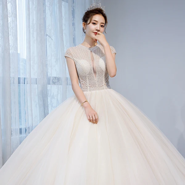 Charmant Champagner Durchsichtige Brautkleider / Hochzeitskleider 2020 Ballkleid Rundhalsausschnitt Ärmel Rückenfreies Perlenstickerei Glanz Tülle Kapelle-Schleppe Rüschen