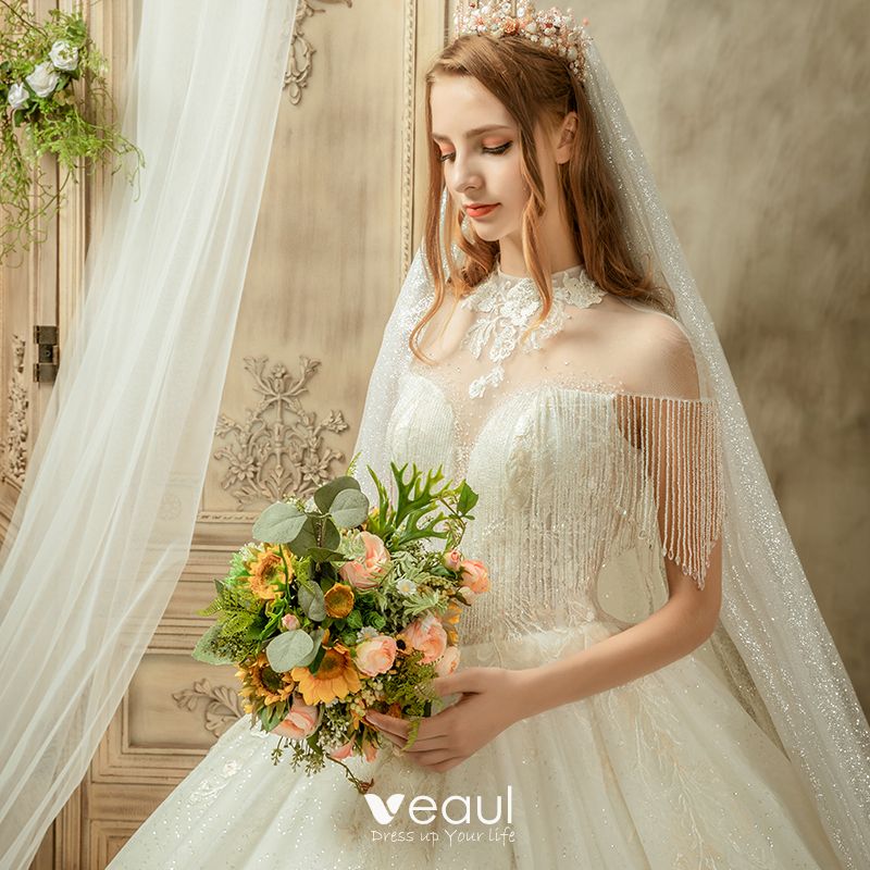 https://img.veaul.com/product/090ae2251c975cc3b2308d215033ea1b/luxury-gorgeous-ivory-see-through-wedding-dresses-2019-ball-gown-high-neck-cap-sleeves-backless-appliques-lace-beading-tassel-glitter-tulle-cathedral-train-ruffle-800x800.jpg